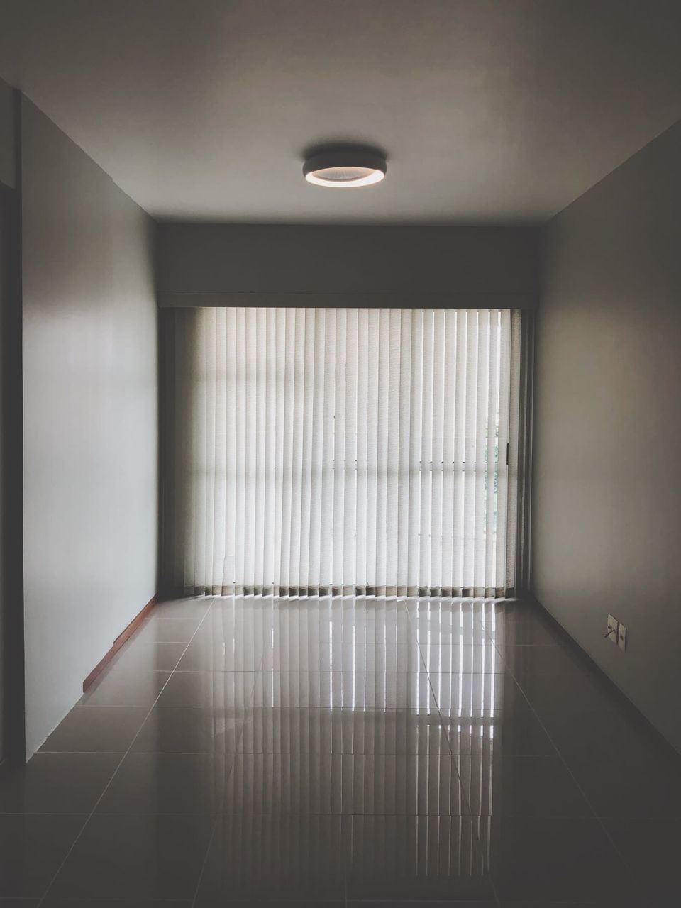 Phòng khách căn hộ trống với rèm sáo ngang ở cửa sổ.
