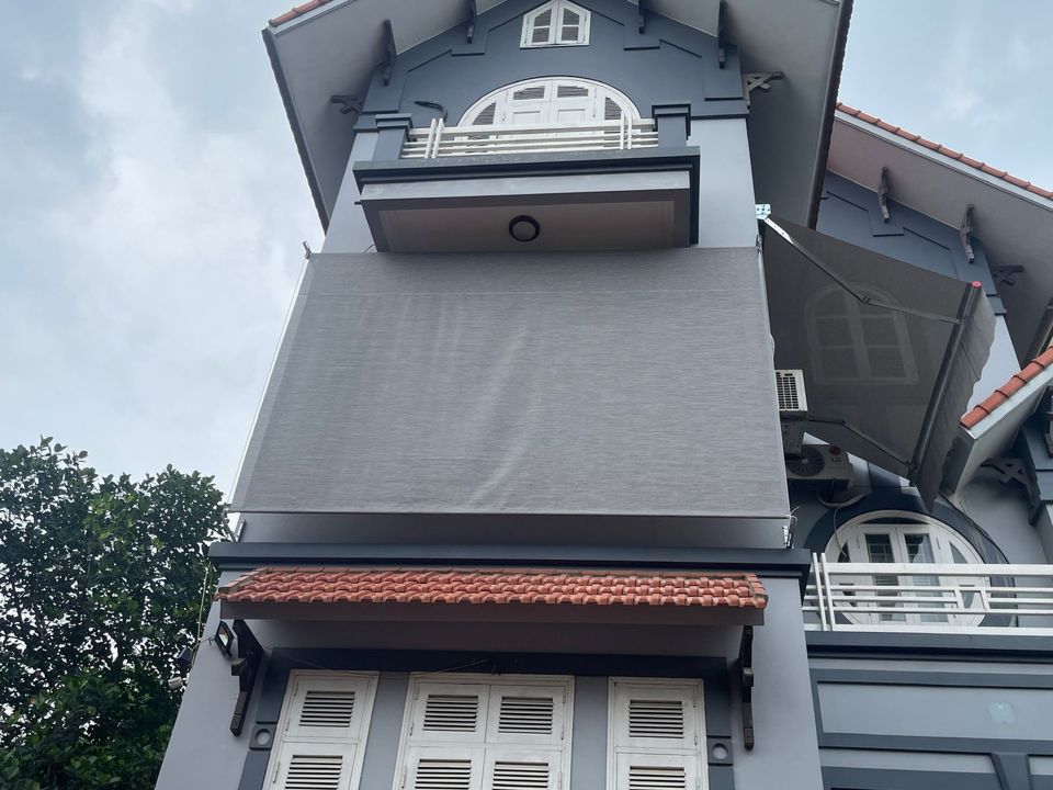 Mảng mành màu tối che khoảng mở dưới mái hiên, phía trước có lan can.